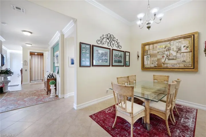 Dining area featuring an inviting chandelier, ornamental molding, and light tile patterned flooring
