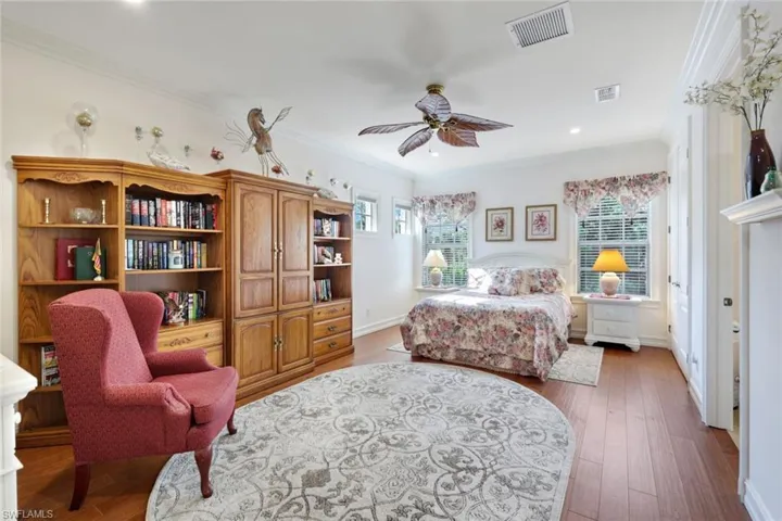 Bedroom featuring ceiling fan, dark wood-type flooring, and crown molding