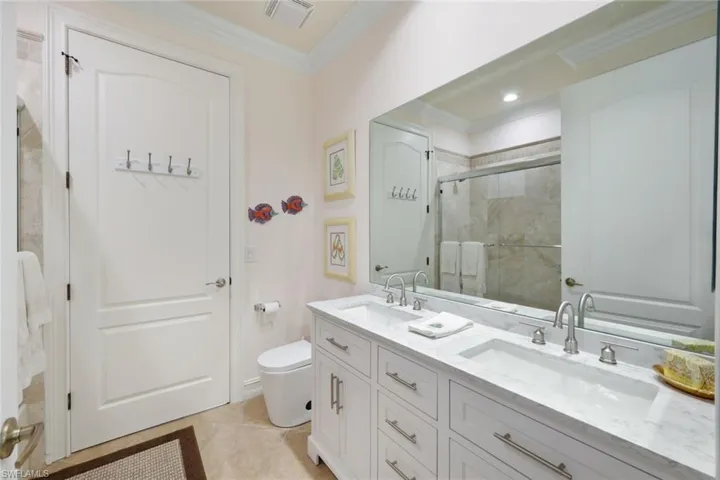 Bathroom with vanity, toilet, ornamental molding, an enclosed shower, and tile patterned flooring
