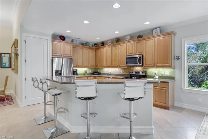 Kitchen featuring appliances with stainless steel finishes, a center island with sink, a kitchen bar, and a wealth of natural light