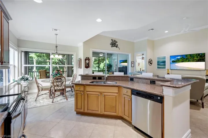 Kitchen featuring pendant lighting, stainless steel appliances, dark stone counters, a kitchen island with sink, and sink