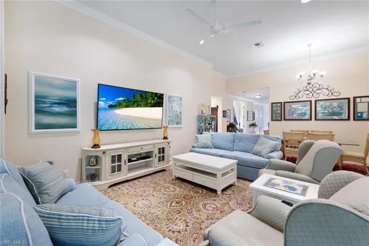 Living room featuring ceiling fan with notable chandelier and crown molding