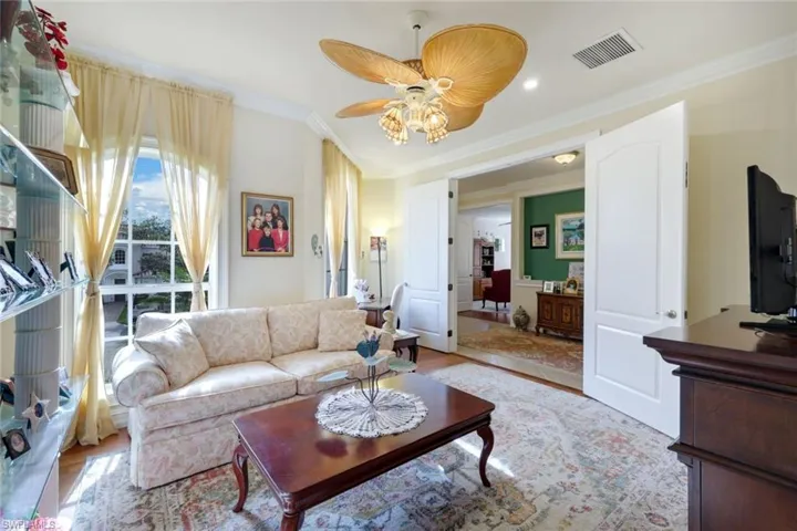 Living room featuring ceiling fan, light wood-type flooring, and crown molding