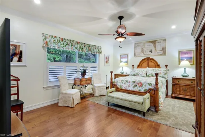 Bedroom with ceiling fan, light wood-type flooring, and ornamental molding