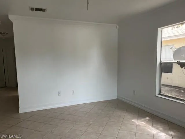 Unfurnished room featuring crown molding and baseboards
