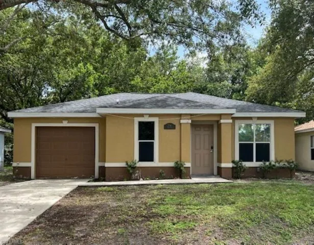 Ranch-style home with a garage, stucco siding, concrete driveway, a shingled roof, and a front lawn