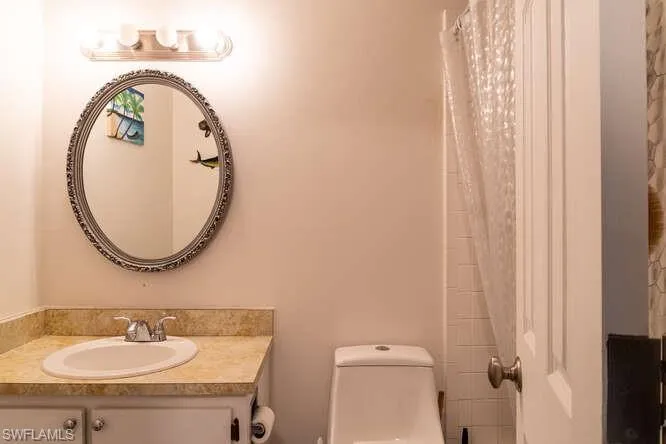 Bathroom with a shower with curtain, vanity, and toilet