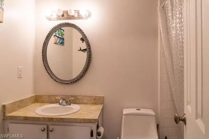 Bathroom featuring vanity, toilet, and curtained shower