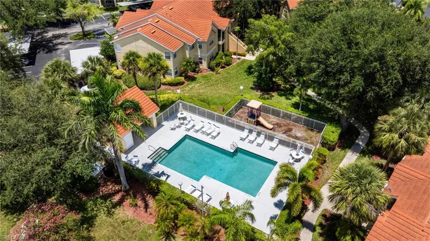 Community pool area featuring a rectangular pool with integrated steps, surrounding concrete decking, and a separate fenced play area