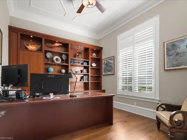 Home office with extensive shelving, storage and wood flooring.