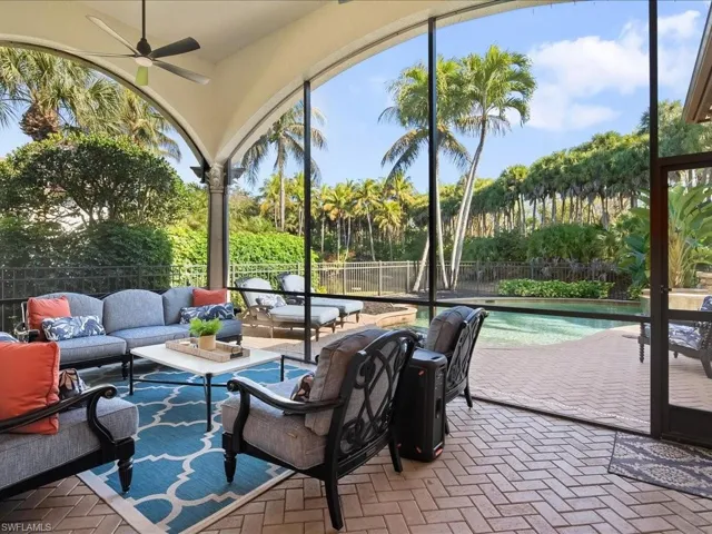 Pavered screened in lanai looking onto the pool area, fenced yard and waterfalls in the adjacent lake.