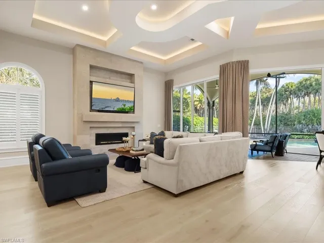 Living room with European White Oak wood floors, a large gas fireplace, and striking custom coffered ceilings detailing.