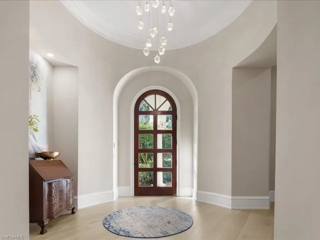 Lovely arched entry to the home with striking light fixture