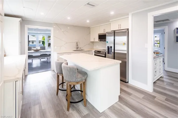 Kitchen featuring stainless steel appliances, light stone counters, light wood finished floors, a kitchen breakfast bar, and a kitchen island