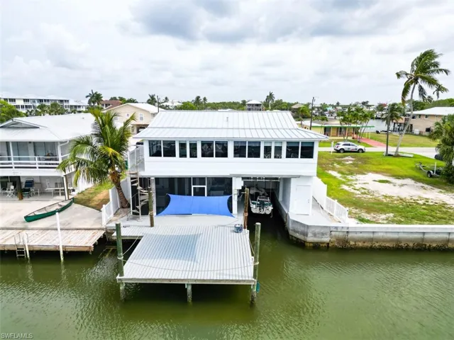 Rear view of house with a water view, a patio, a sunroom, stairs, and a metal roof