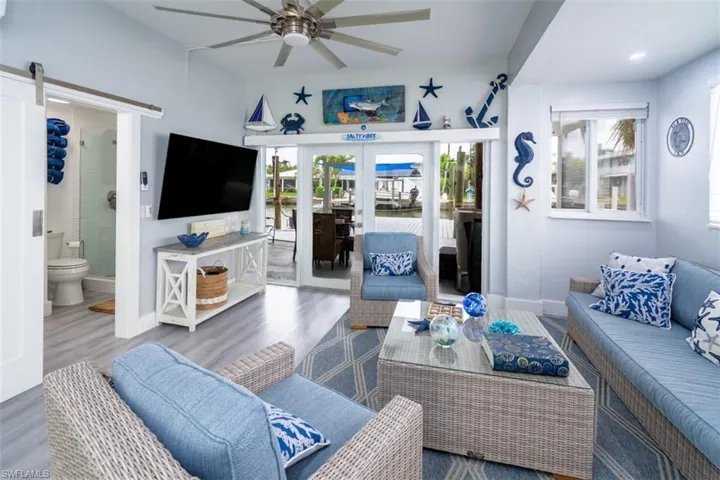 Living room with wood finished floors, plenty of natural light, ceiling fan, and french doors