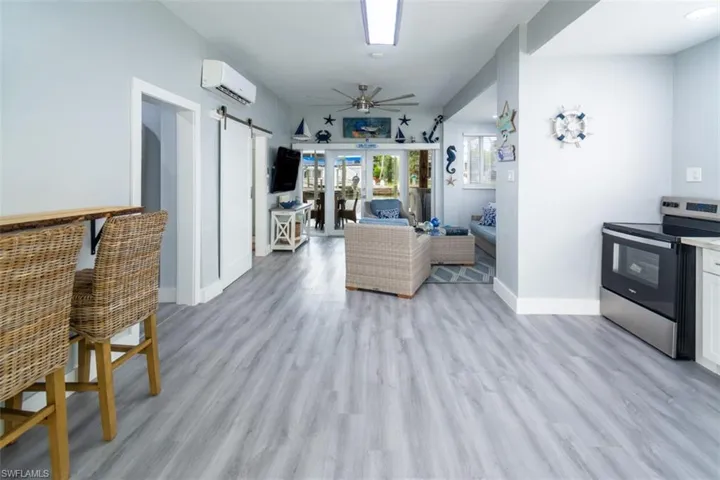 Kitchen with stainless steel electric stove, a ceiling fan, a barn door, light countertops, and an AC wall unit