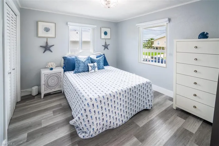Bedroom featuring ornamental molding, multiple windows, and wood finished floors