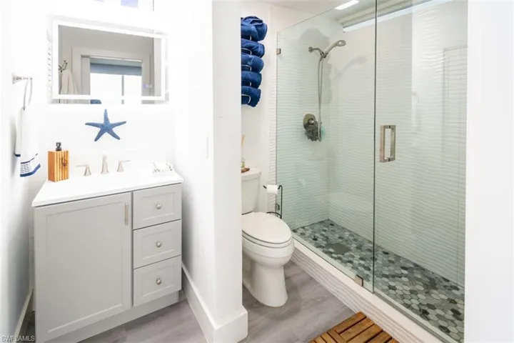 Bathroom with vanity, a shower stall, and light wood-type flooring