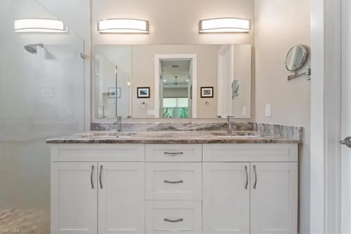Full bathroom featuring a tile shower and double vanity