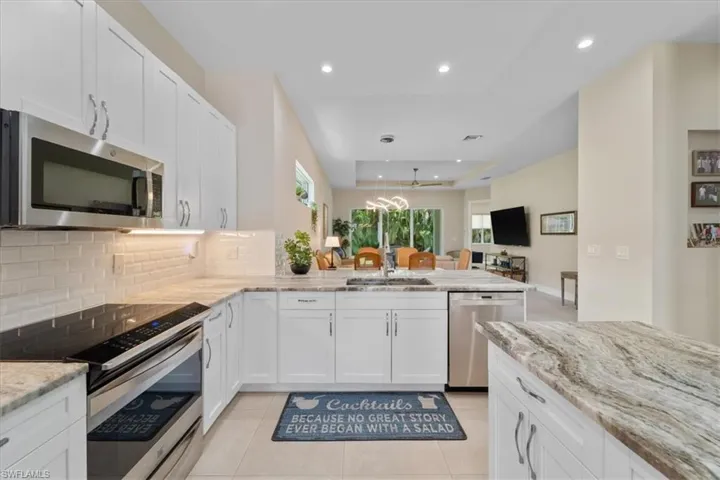 Kitchen with stainless steel appliances, a peninsula, tasteful backsplash, white cabinetry, and recessed lighting