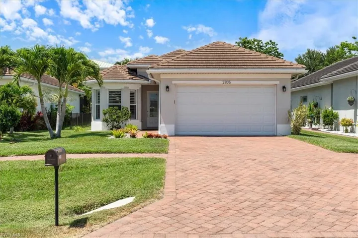 View of front of house featuring an attached garage, a tile roof, decorative driveway, a front yard, and stucco siding