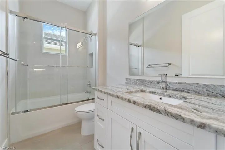 Bathroom with vanity, shower / bath combination with glass door, and tile patterned flooring