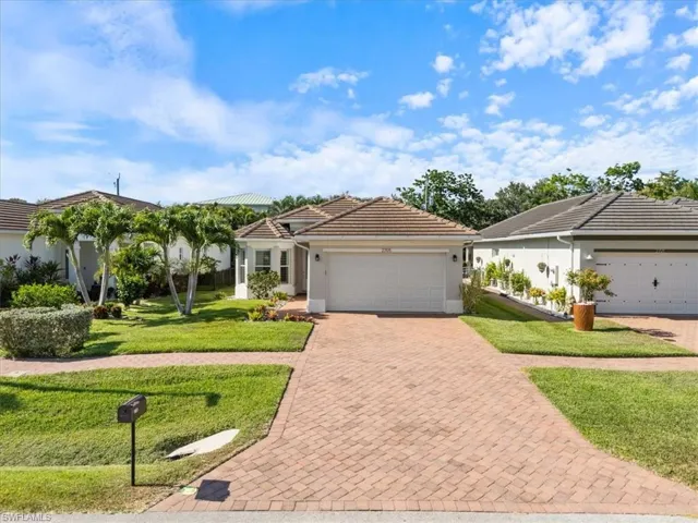 Single story home with a tile roof, stucco siding, an attached garage, a front yard, and decorative driveway