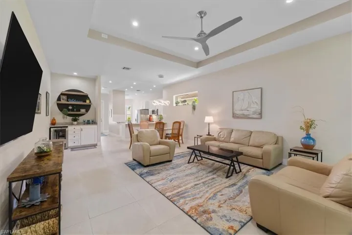 Living area featuring ceiling fan, recessed lighting, light tile patterned flooring, and a raised ceiling