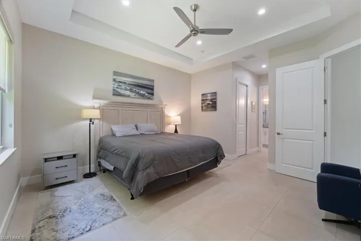 Bedroom featuring a tray ceiling, recessed lighting, ceiling fan, and light tile patterned floors