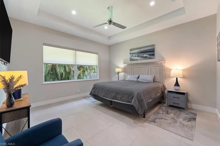 Bedroom with a raised ceiling, recessed lighting, ceiling fan, and light tile patterned flooring