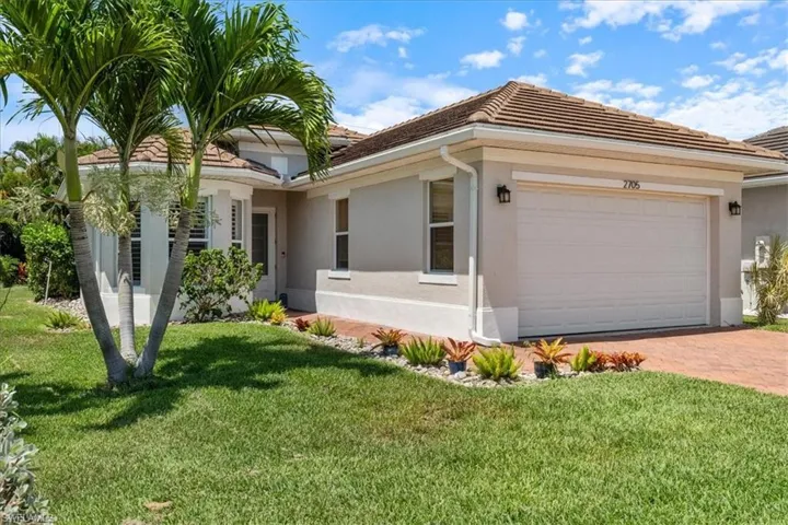 Single story home featuring stucco siding, a garage, a front yard, and decorative driveway