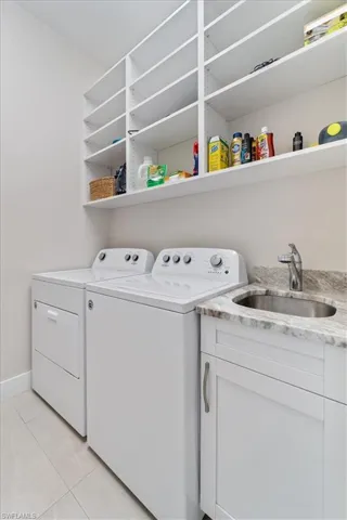 Laundry area with washer and clothes dryer, light tile patterned floors, and cabinet space
