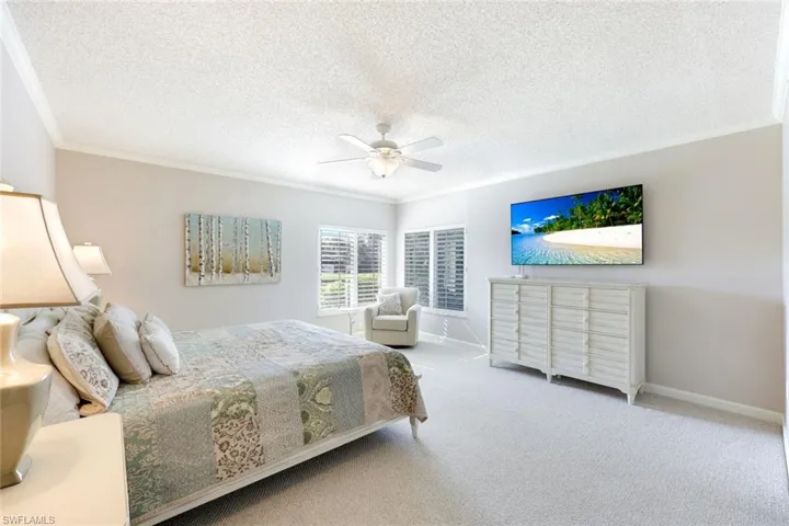 Bedroom featuring crown molding, a textured ceiling, carpet, and a ceiling fan