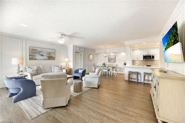 Living area featuring a decorative wall, a textured ceiling, a ceiling fan, light wood-style floors, and crown molding