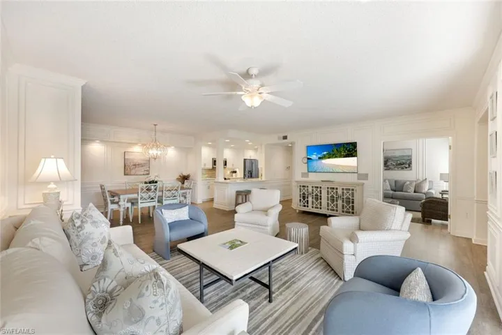 Living area featuring a decorative wall, wood finished floors, a chandelier, and a ceiling fan