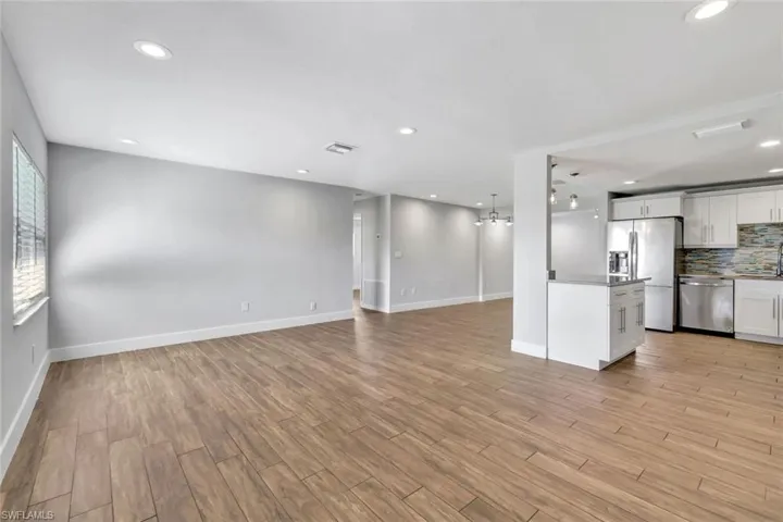 Unfurnished living room featuring a chandelier, wood tiled floors, and recessed lighting