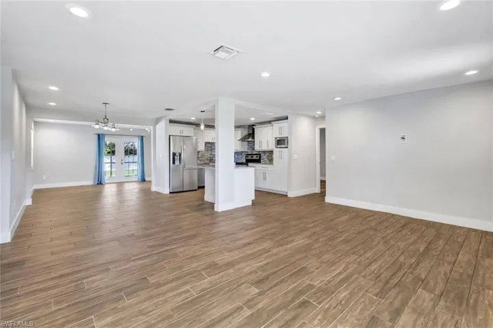 Unfurnished living room featuring recessed lighting, wood tiled floors, french doors, and a chandelier