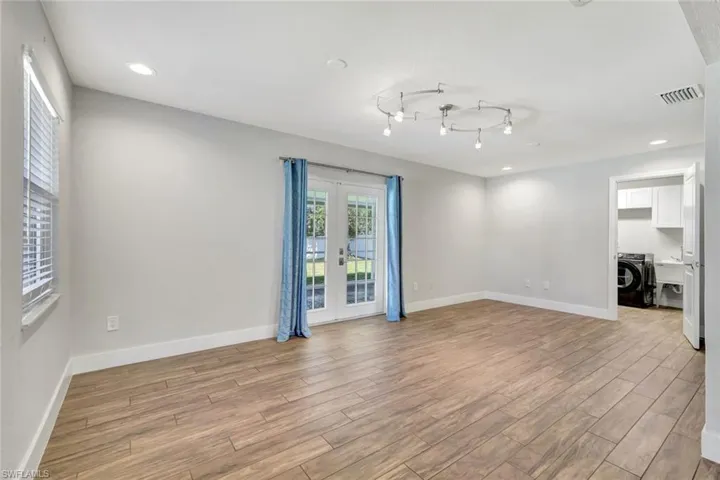 Unfurnished living room featuring recessed lighting, french doors, washer / clothes dryer, and light wood-style flooring