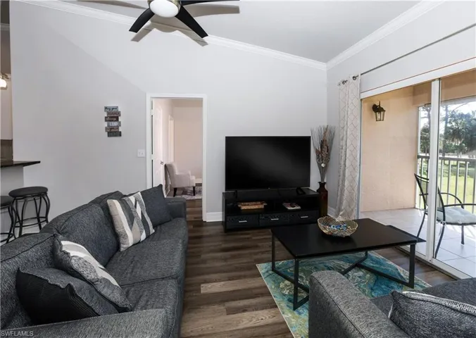 Living room featuring ornamental molding, wood finished floors, a ceiling fan, and baseboards