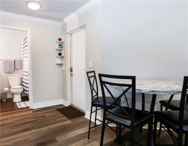 Dining room featuring dark wood-style floors, ornamental molding, and baseboards