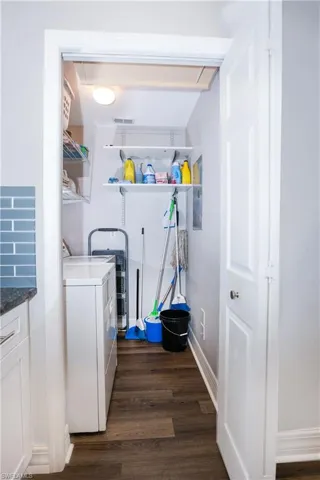 Laundry area featuring dark wood finished floors, washing machine and clothes dryer, visible vents, laundry area, and baseboards