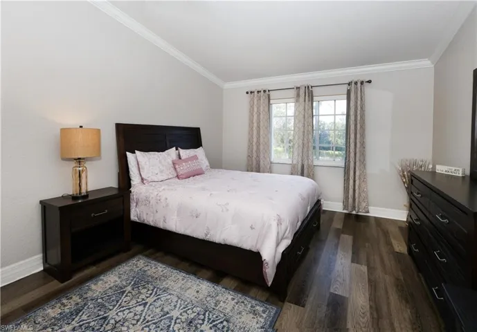 Bedroom with baseboards, ornamental molding, and dark wood-type flooring