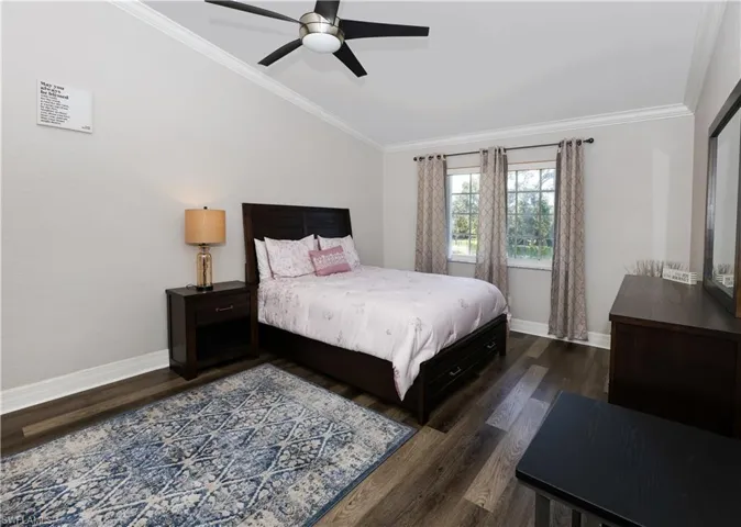 Bedroom with baseboards, ornamental molding, vaulted ceiling, and dark wood-style flooring