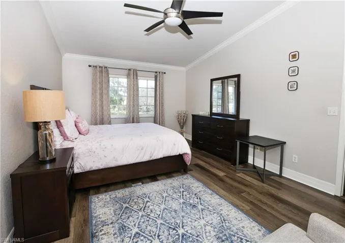 Bedroom with vaulted ceiling, crown molding, baseboards, and wood finished floors