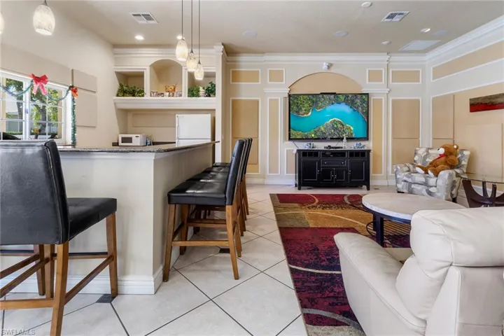 Kitchen featuring white appliances, light tile patterned floors, visible vents, and a kitchen breakfast bar