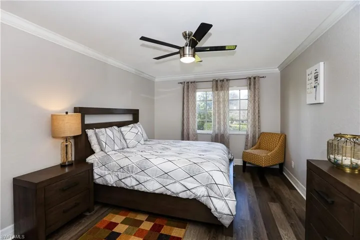 Bedroom featuring baseboards, ceiling fan, dark wood finished floors, and crown molding