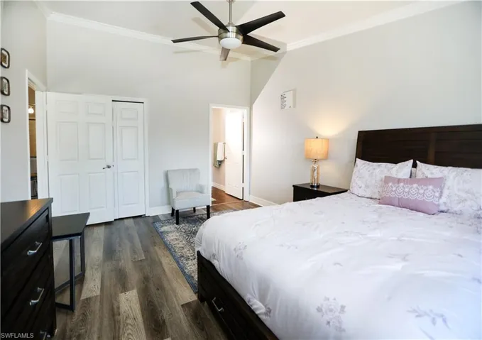 Bedroom featuring dark wood-type flooring, baseboards, vaulted ceiling, ornamental molding, and a closet