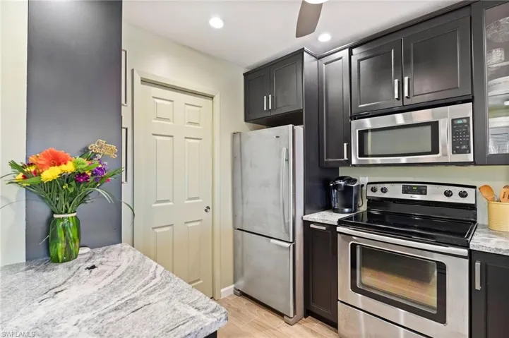 Kitchen featuring light wood-type flooring, stainless steel appliances, light granite counters, and ceiling fan