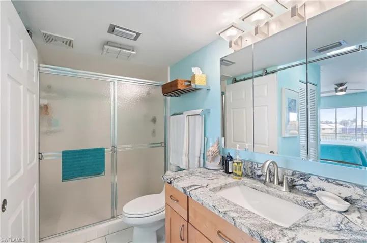 Primary Bathroom with granite vanity, toilet, walk in shower, and tile patterned flooring